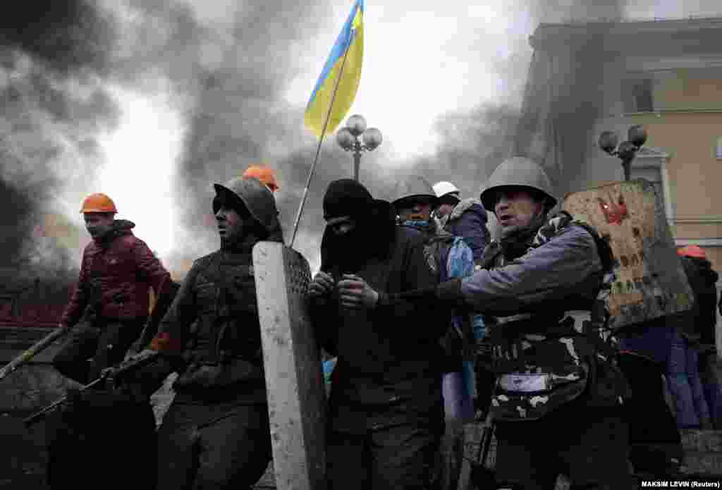 Anti-government protesters lead a riot policeman away from Independence Square in Kyiv on February 20, 2014.