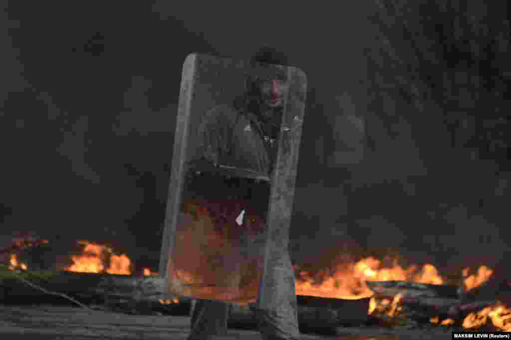 A pro-Russia protester holds a riot shield at a checkpoint as smoke rises from burning tires in Slovyansk, Ukraine, on April 13, 2014. That year, Russia&#39;s military began backing separatist forces that eventually, after battles with Ukrainian government troops, took over parts of Ukraine&#39;s Donetsk and Luhansk regions.