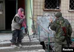 Местный житель разговаривает с военнослужащим пророссийских войск возле жилого дома, поврежденного во время украинско-российского конфликта в осажденном южном портовом городе Мариуполь, Украина, 31 марта 2022 года