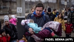 A man carries a girl as he and other families arrive at a train station to flee the eastern city of Kramatorsk, in the Donbas region, on April 4.
