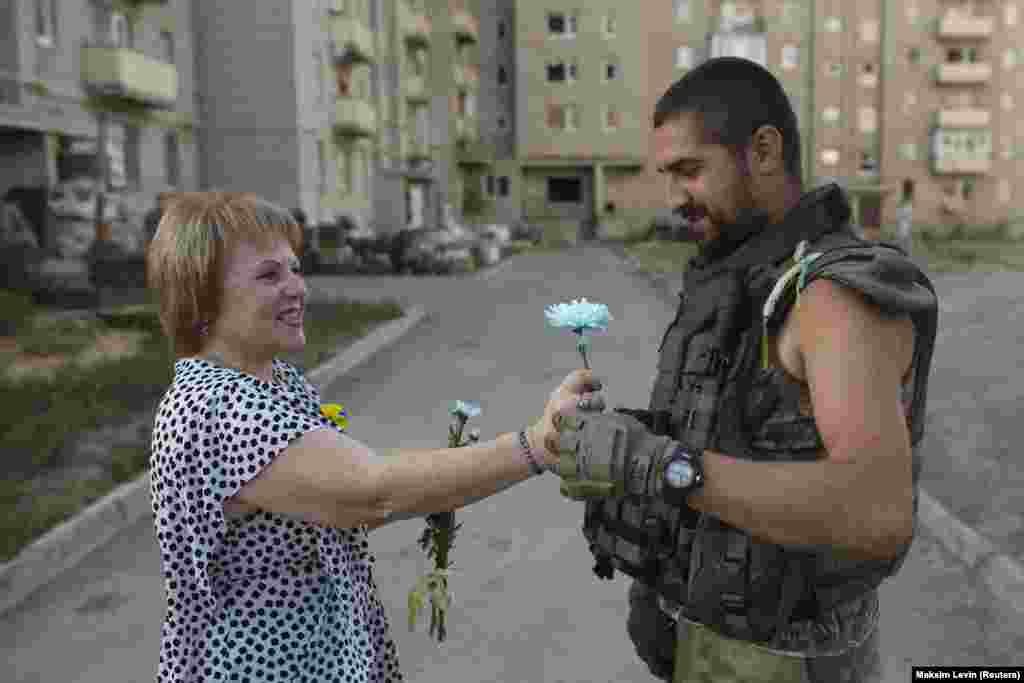 Женщина дарит цветок украинскому военнослужащему во время празднования Дня Независимости в Авдеевке, городе в Донецкой области Украины, 24 августа 2015 года