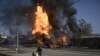مردی همراه با وسایلش در حال فرار از محلی در شهر خارکیف که مورد حمله نیروهای ارتش روسیه قرار گرفته و در آتش می‌سوزد.