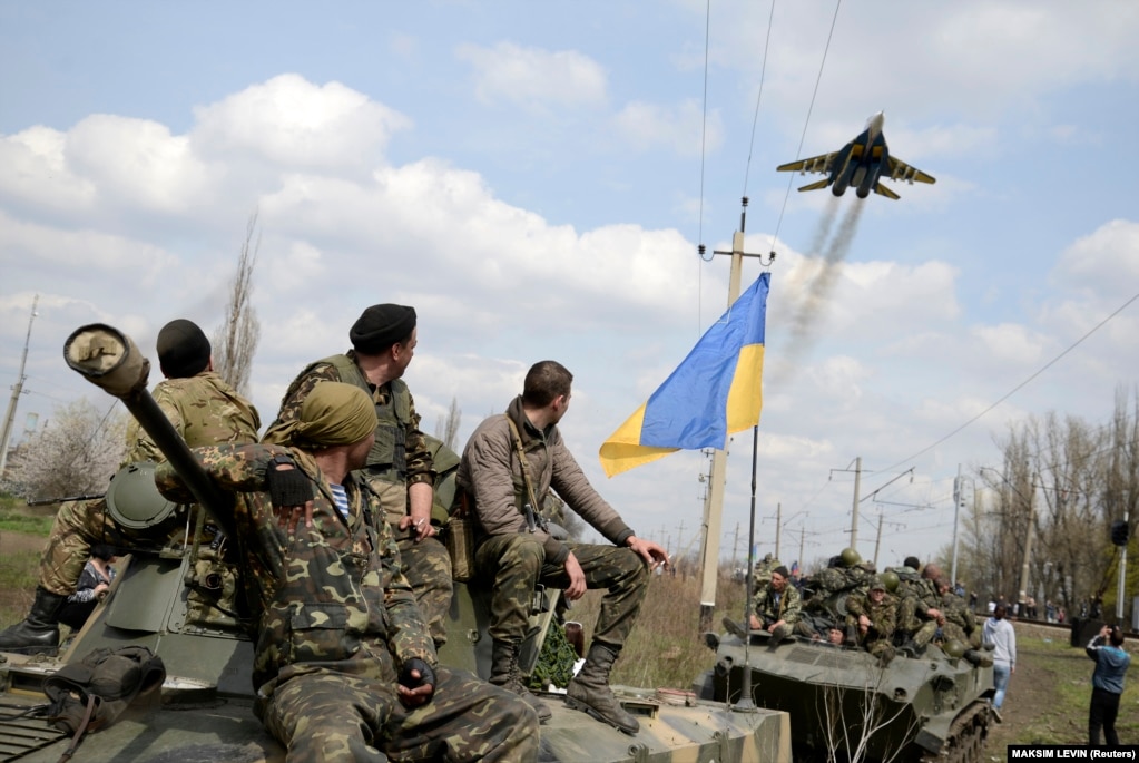 Ushtarët ukrainas duke shikuar një avion ushtarak ukrainas duke fluturuar, teksa qëndronin mbi tanke në Kramatorsk, në lindje të Ukrainës, më 16 prill 2014.