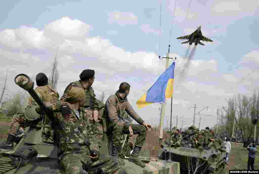 Ukrainian soldiers watch a Ukrainian military jet fly over while they sit on top of armored personnel carriers in Kramatorsk in eastern Ukraine on April 16, 2014.&nbsp;
