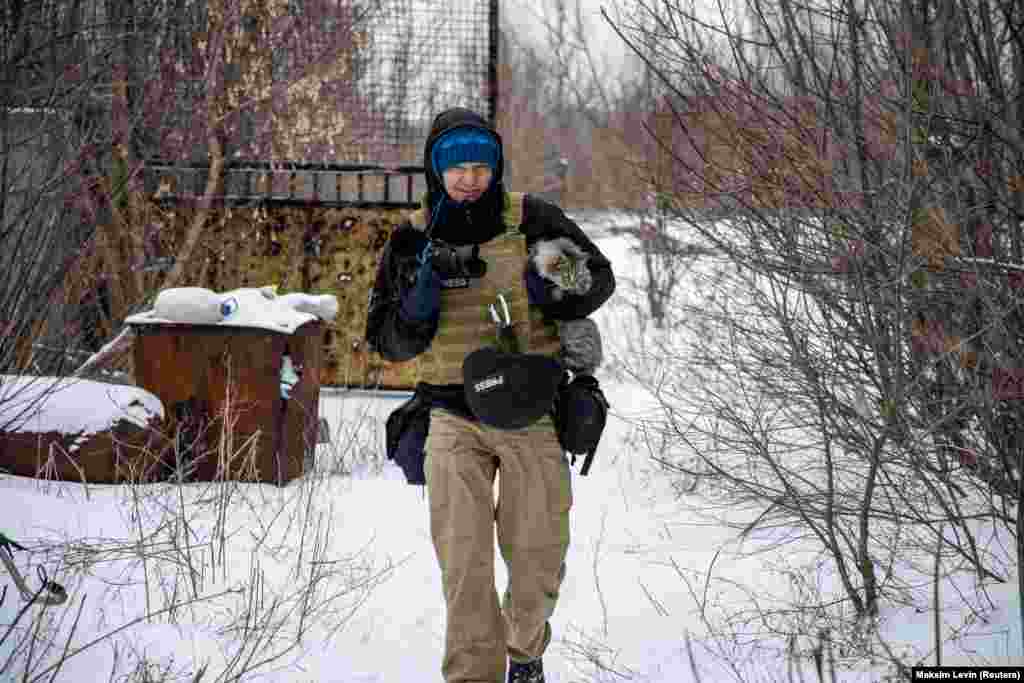 Ukrainian photographer Maksim Levin carries a cat near the line of separation from Russia-backed separatists in Ukraine&#39;s Donetsk region on January 25, 2022.