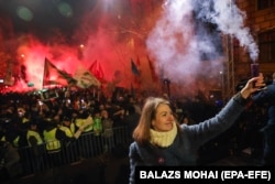 Anna Donath, then the deputy chairwoman of the opposition Momentum Movement, holds up a smoke grenade during an anti-government protest in downtown Budapest in December 2018.