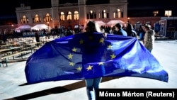 Európai uniós zászlót magára terítő nő az ellenzéki eredményvárón a 2022. április 3-i választás estéjén Budapesten