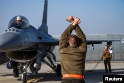 Американський військовий вказує пілоту ВПС США гальмувати винищувач F-16 після приземлення поблизу бази в Фетешти, Румунія. Лютий 2022 року