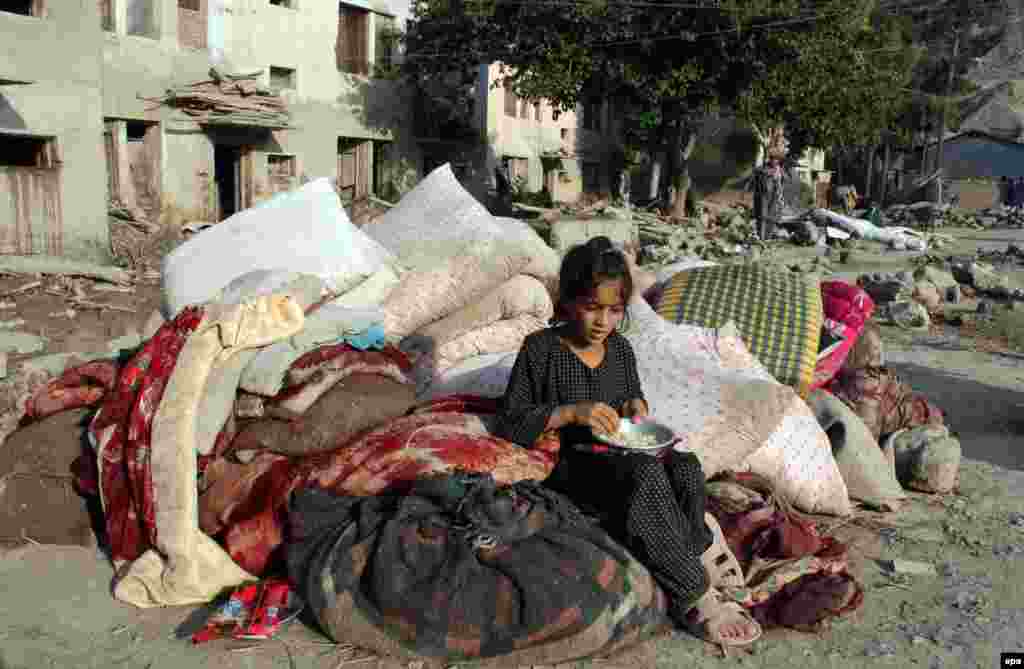 An Afghan girl affected by the floodwaters sits beside her belongings near damaged houses in the Sarobi district of Kabul. 