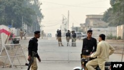 FILE: Pakistani policemen check a motorcyclist as they cordon off a street beside a bank building a day after a suicide bomb attack in Rawalpindi in November 2009.