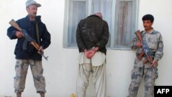 Afghan policemen guards an arrested drug smuggler in Herat.