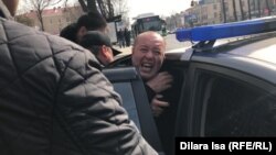 Полиция силой заталкивает активиста Мурата Аштаева в машину. Шымкент, 1 марта 2020 года.