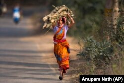 O femeie din India cară lemne de foc după o zi de muncă într-un câmp de orez la marginea orașului Gauhati - 1 februarie 2019