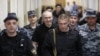 Mikhail Khodorkovsky (center, smiling) is escorted to court in Moscow in June 2011.
