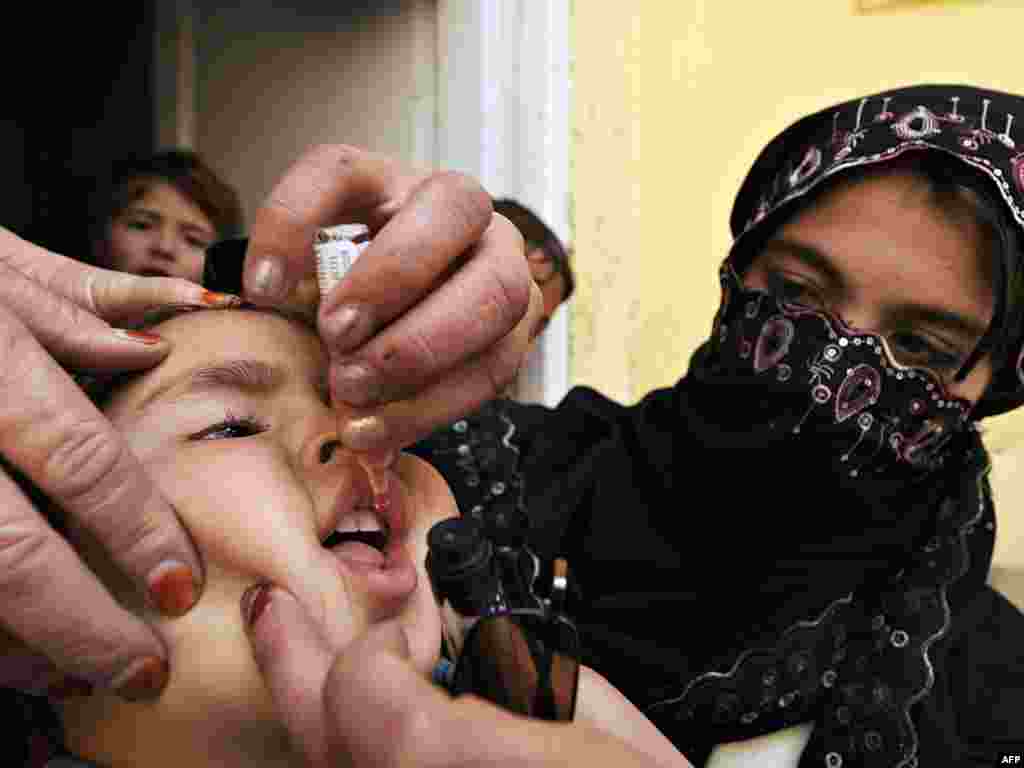  An Afghan health worker drops polio vaccine into the mouth of a child on the second day of a vaccination campaign in Kabul on March 16, 2009. A new three-day nationwide immunization campaign against polio began March 15 in a joint operation with the Ministry of Public Health, the United Nations Children's Fund (UNICEF) and the World Health Organization (WHO). Afghanistan is one of only of a handful of countries in the world that still has the crippling polio virus with new cases reported every year, most often in areas where insurgent threats mean vaccinators are unable to reach all children.