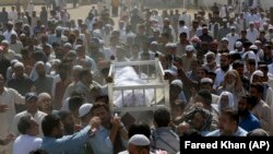 People carry the body of a victim of a toxic gas leak during his funeral prayer in Karachi on February 17.