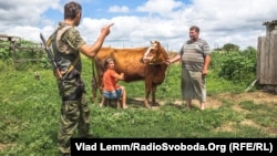 Архівне фото: український військовий розпитує мешканців Чермалика про наслідки обстрілу