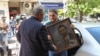 Алекбер Абил от младежката структура на ДПС-Доган държи портрет на почетния лидер на движението Ахмед Доган. Това се случва, докато служители на областната администрация в София запечатват партийната централа на ДПС, 19 май 2025 г.