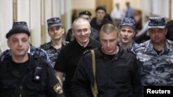 Mikhail Khodorkovsky (center, smiling) is escorted to court in Moscow in June 2011.