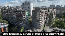 Firefighters work at a site of the apartment building damaged during a Russian missile and drone strike in Kyiv on May 14, 2026.