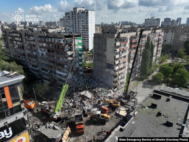 Yanğınsöndürənlər Rusiyanın raket və dron hücumu zamanı dağılmış yaşayış binasının yerində işləyirlər.