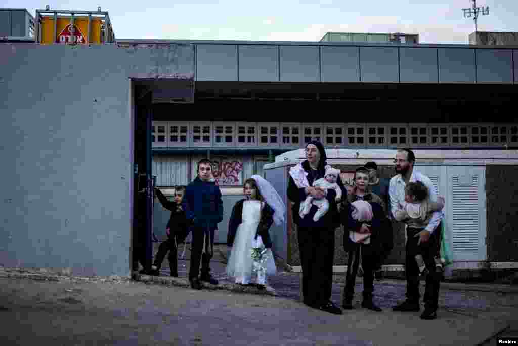 O familie evreiască ultraortodoxă stă în fața unui adăpost antiaerian în Haifa.