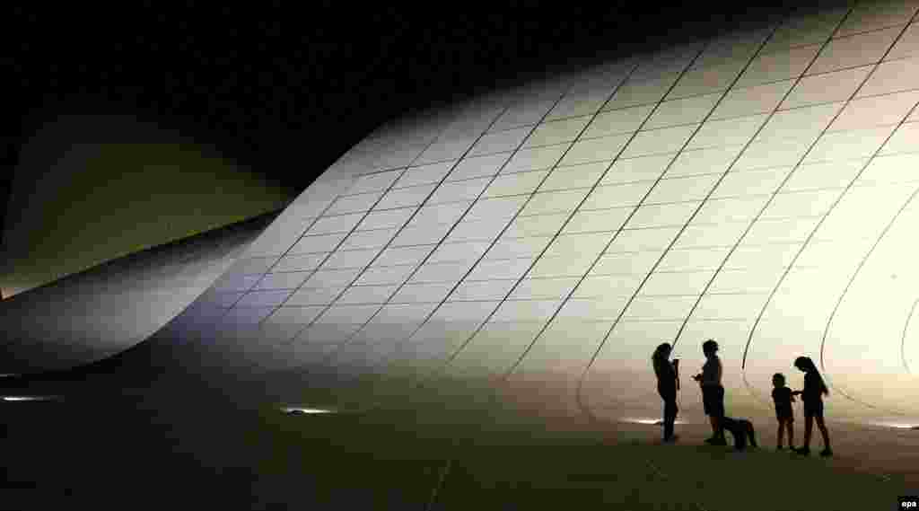 People stand in front the Heydar Aliyev Cultural Center in Baku, Azerbaijan. (epa/Zurab Kurtsikidze)