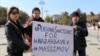 Участники протеста держат плакат с призывом ввести санкции в отношении бывшего президента Казахстана Нурсултана Назарбаева и главы КНБ Карима Масимова
