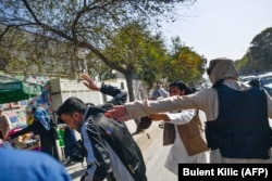 A member of the Taliban attacks a journalist covering the women's protest.