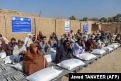 Ljudi sjede pored džakova žitarica koje je Svjetski program za hranu distribuirao u Kandaharu 19. oktobra 2021.