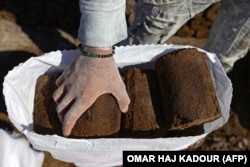 На заводе в сирийской провинции Идлиб рабочий разгружает мешки с жмыхом, известным в Сирии как "бирин" — легковоспламеняющимся продуктом, изготавливаемым из отходов при получении оливкового масла. В стране из-за нехватки другого топлива он активно используется для отопления