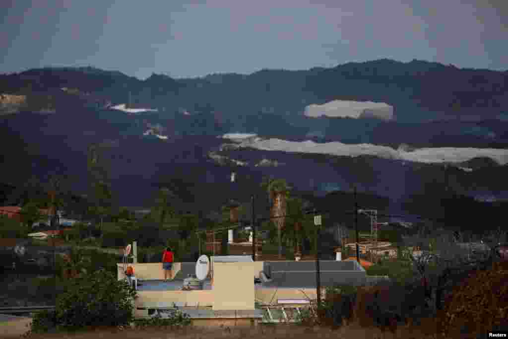 Жінка дивиться з даху будинку на дим від лави вулкану Кумбре-В&#39;єха. Лава досягла містечка Ла-Лагуна на Канарському острові Ла-Пальма, Іспанія, 21 жовтня 2021 року