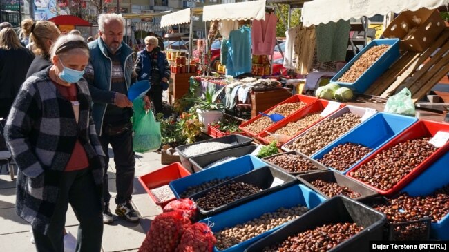 Qytetarë të Prishtinës shikojnë çmimet e produkteve në një treg.