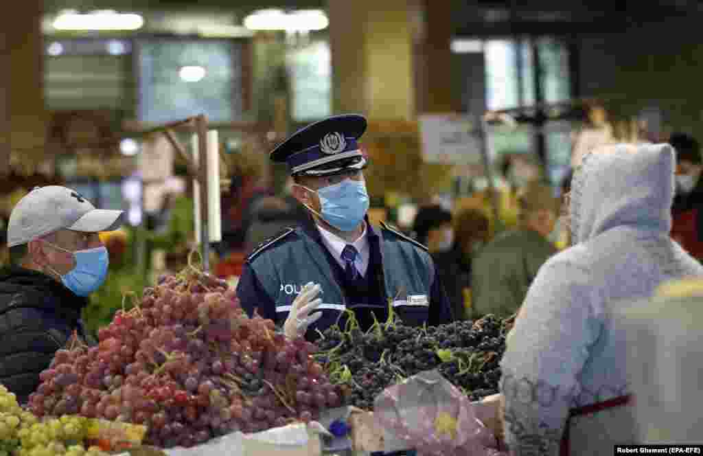 A policeman speaks to fruit sellers at a market in Bucharest on October 16. President Klaus Iohannis suggested restrictive new measures are likely. &quot;Whether we are talking about the green certificate or other measures to reduce mobility and human interaction, we must not waste any more time...no matter how unpopular it may seem,&quot; he said on October 19.&nbsp;