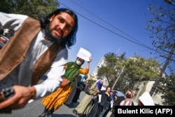 A member of the Taliban attacks Turkish photographer Bulent Kilic as the women's march descended into violence.