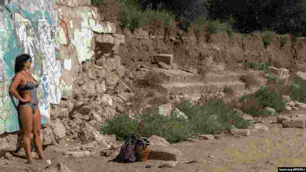 Женщина &laquo;ловит загар&raquo; под последними теплыми лучами осеннего солнца возле подпорной стенки