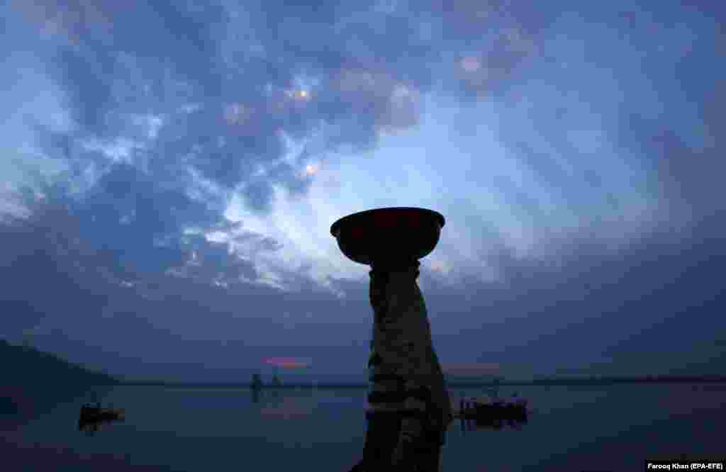 A Kashmiri woman carries a utensil on her head as she walks on the banks of Dal Lake at sunset in Srinagar, the summer capital of Indian Kashmir, on February 7. (epa-EFE/Farooq Khan)