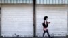 IRAN -- An Iranian woman wearing a protective mask due to the COVID-19 pandemic walks past a shuttered shop on Enghelab suqare in the center of Tehran, May 16, 2021