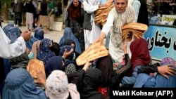 شماری از زنان و کودکان فقیر در کابل در حال دریافت نان خیرات 