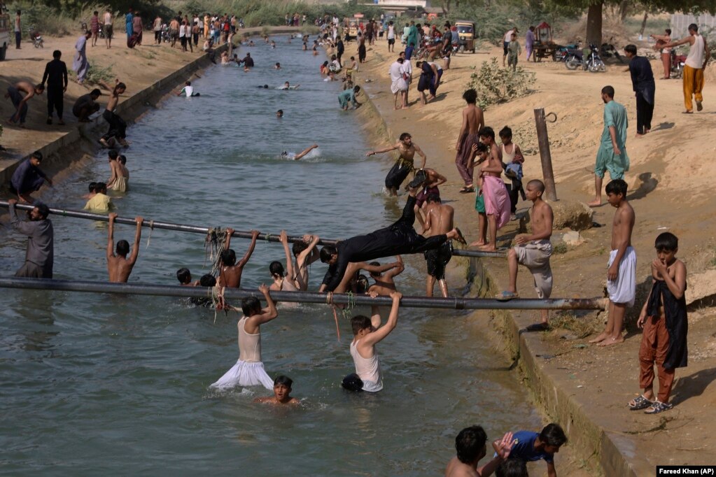 Njerëzit notojnë në një kanal në Karaçi të Pakistanit, ku temperaturat arritën në 37 gradë Celsius, më 6 prill.