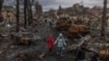 UKRAINE -- Vladyslava Liubarets (C), a Bucha resident, walks with her family past destroyed Russian military machinery, to meet her sister whom she did not see since the beginning of the Russian invasion, in Bucha, the town which was retaken by the Ukrain