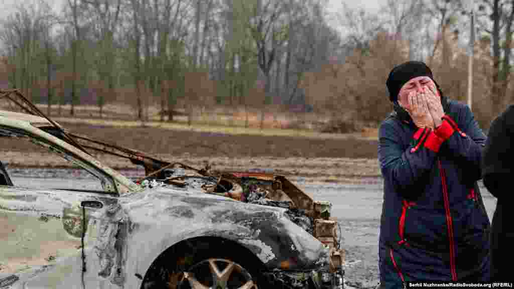 A resident of the village of Nova Basan reacts to seeing the body of the civilian near the burned-out car.