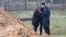 Oameni în apropierea unei gropi comune descoperite în localitatea Bucea de lângă Kiev. 