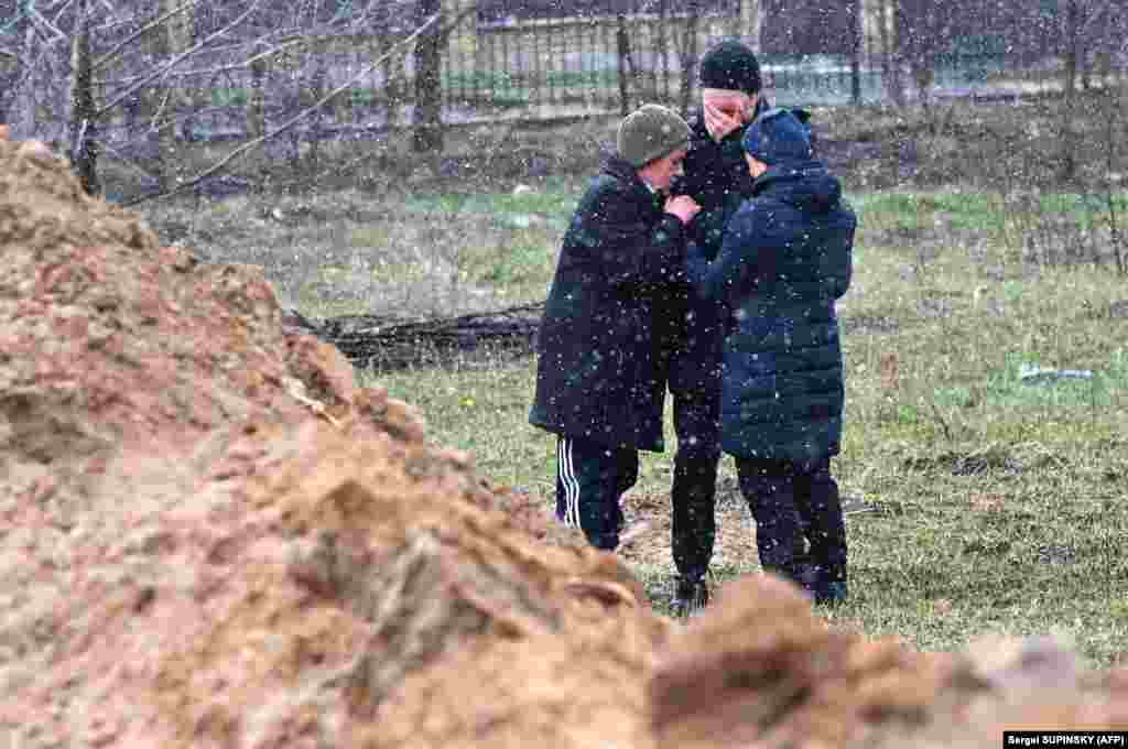 Disa njerëz duke qarë pranë një varri masiv më 3 prill 2022. Kievi po ashtu raportoi se 175 persona u gjetën në disa varreza masive dhe në disa dhoma torturash.