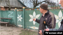 Мешканець села Іванівка показує напис, який зробили на його загорожі російські солдати