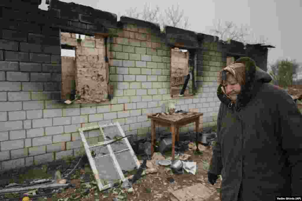 Egy asszony sétál az orosz csapatok által megszállt falu, Andrijivka lerombolt épületei mellett április 5-én