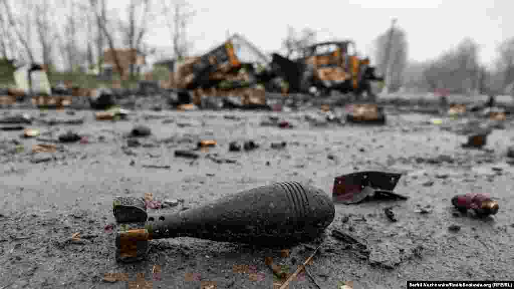 A Russian 82mm mortar shell lies on the ground near destroyed Russian military equipment.
