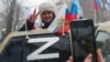 Жена от анексирания Крим позира до знака Z, поставен върху автомобил. Буквата Z се превърна в символ на подкрепата за руската военна инвазия в Украйна. 18 март 2022 г.