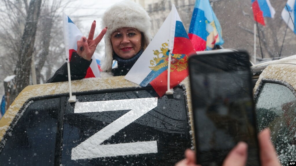 Жена от анексирания Крим позира до знака Z, поставен върху автомобил. Буквата Z се превърна в символ на подкрепата за руската военна инвазия в Украйна. 18 март 2022 г.