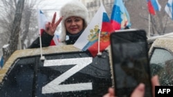 Жена от анексирания Крим позира до знака Z, поставен върху автомобил. Буквата Z се превърна в символ на подкрепата за руската военна инвазия в Украйна. 18 март 2022 г.